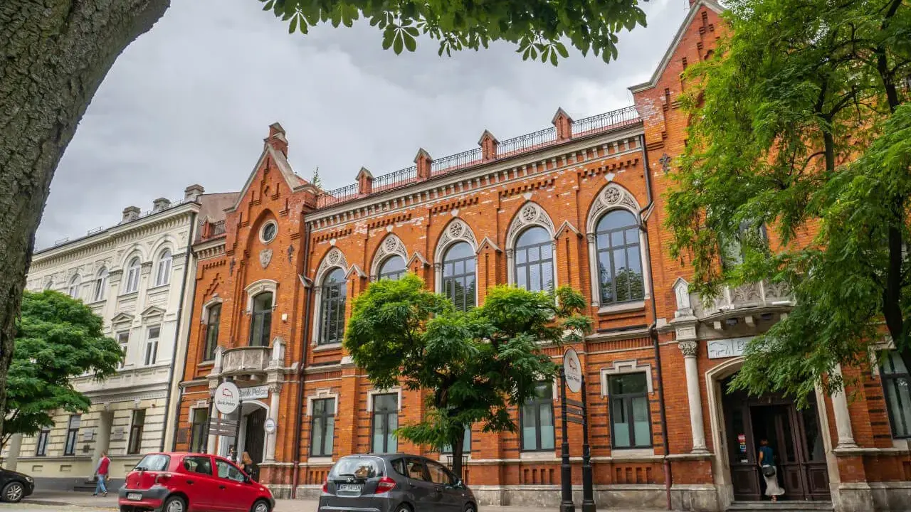 Architektura w Radomiu zachwyca. Czerwona kamienica z ozdobnymi oknami i biały budynek obok to ciekawe radomskie atrakcje.