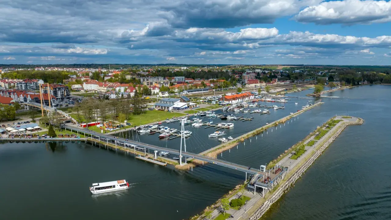 Idealne mazury na weekend: malownicza przystań z łodziami, nowoczesny most i urokliwe miasteczko nad jeziorem.