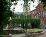 Fontanna i zielone arkady w parku miejskim, w tle zabytkowa architektura. Leszno atrakcje zachęcają do odpoczynku.