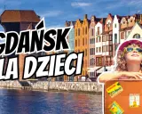 Gdańsk dla dzieci: uśmiechnięta dziewczynka w okularach przeciwsłonecznych na tle kamieniczek i dźwigu.