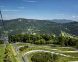 Tor saneczkowy na szlak na Czantorię z Ustronia, z widokiem na zielone wzgórza i niebo.