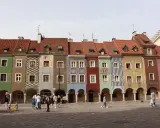 Kolorowe kamienice na Rynku w Poznaniu, sercu Polski. Ludzie spacerują po brukowanym placu.