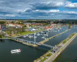 Idealne mazury na weekend: malownicza przystań z łodziami, nowoczesny most i urokliwe miasteczko nad jeziorem.