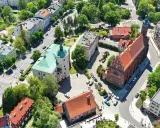 Słupsk atrakcje: zamek Książąt Pomorskich z zielonym dachem i ceglany kościół. W tle budynki mieszkalne i drzewa.