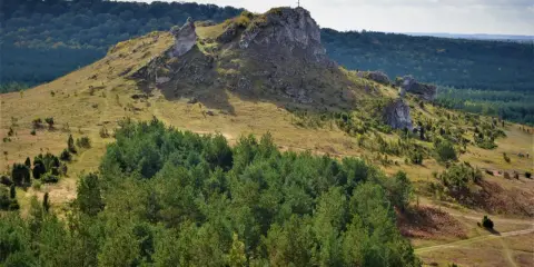 Góra Biakło z krzyżem na szczycie, otoczona lasami i skalistymi wzniesieniami.