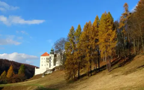 Jesienny krajobraz z zamkiem na skale. Trasa turystyczna Maczuga Herkulesa prowadzi przez malownicze wzgórza porośnięte złotymi drzewami.