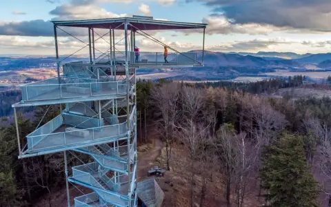 Wieża widokowa na Trójgarbie zaprasza na spacer po szlakach. Dwie osoby podziwiają panoramę z platformy.