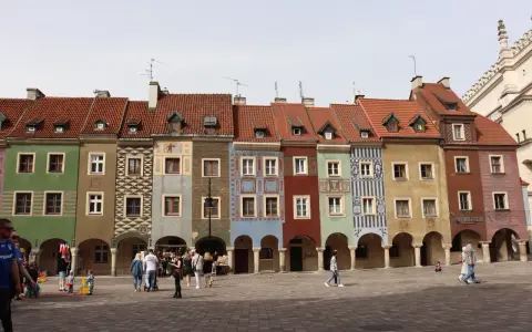 Kolorowe kamienice na Rynku w Poznaniu, sercu Polski. Ludzie spacerują po brukowanym placu.