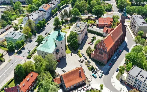 Słupsk atrakcje: zamek Książąt Pomorskich z zielonym dachem i ceglany kościół. W tle budynki mieszkalne i drzewa.