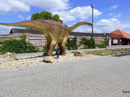 Dziecko podziwia ogromnego dinozaura w JuraParku. Jura Krakowsko-Częstochowska oferuje wspaniałe atrakcje dla dzieci.