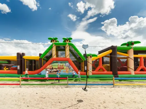Kolorowy dmuchany plac zabaw z motywem dżungli, oferujący mnóstwo atrakcji dla dzieci w Niechorzu.