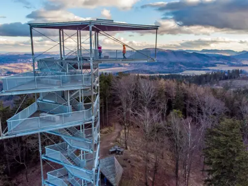 Wieża widokowa na Trójgarbie zaprasza na spacer po szlakach. Dwie osoby podziwiają panoramę z platformy.