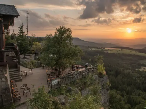 Widok z tarasu restauracji na Górach Stołowych w Czechach o zachodzie słońca.