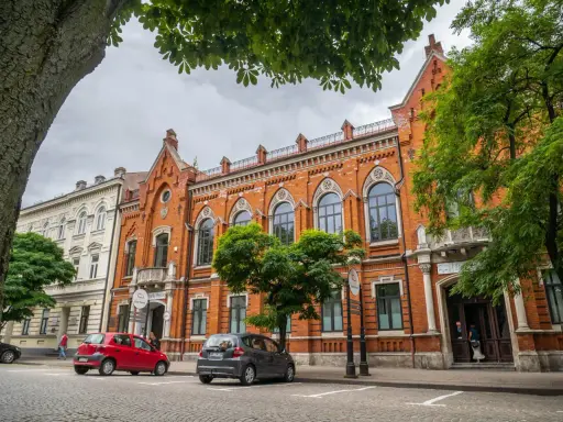 Architektura w Radomiu zachwyca. Czerwona kamienica z ozdobnymi oknami i biały budynek obok to ciekawe radomskie atrakcje.