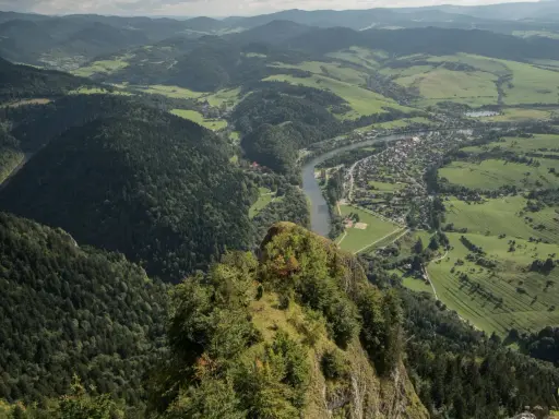 Widok z góry na dolinę Dunajca, malowniczą wieś i zielone wzgórza. Trasa na Trzy Korony oferuje zapierające dech w piersiach krajobrazy.