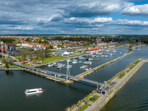 Idealne mazury na weekend: malownicza przystań z łodziami, nowoczesny most i urokliwe miasteczko nad jeziorem.