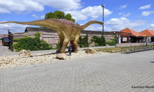 Dziecko podziwia ogromnego dinozaura w JuraParku. Jura Krakowsko-Częstochowska oferuje wspaniałe atrakcje dla dzieci.