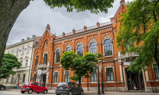 Architektura w Radomiu zachwyca. Czerwona kamienica z ozdobnymi oknami i biały budynek obok to ciekawe radomskie atrakcje.