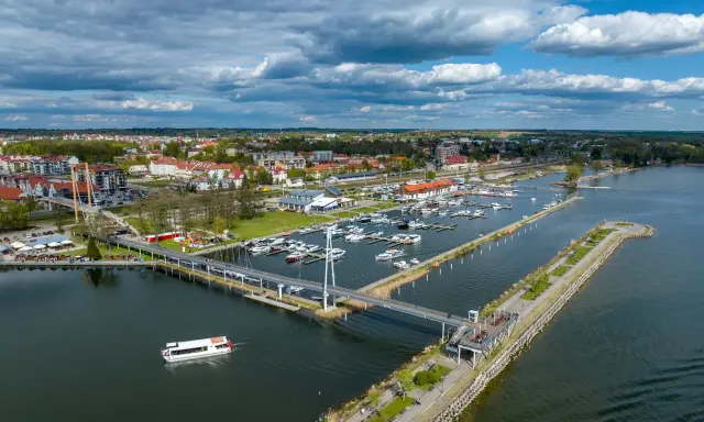 Idealne mazury na weekend: malownicza przystań z łodziami, nowoczesny most i urokliwe miasteczko nad jeziorem.