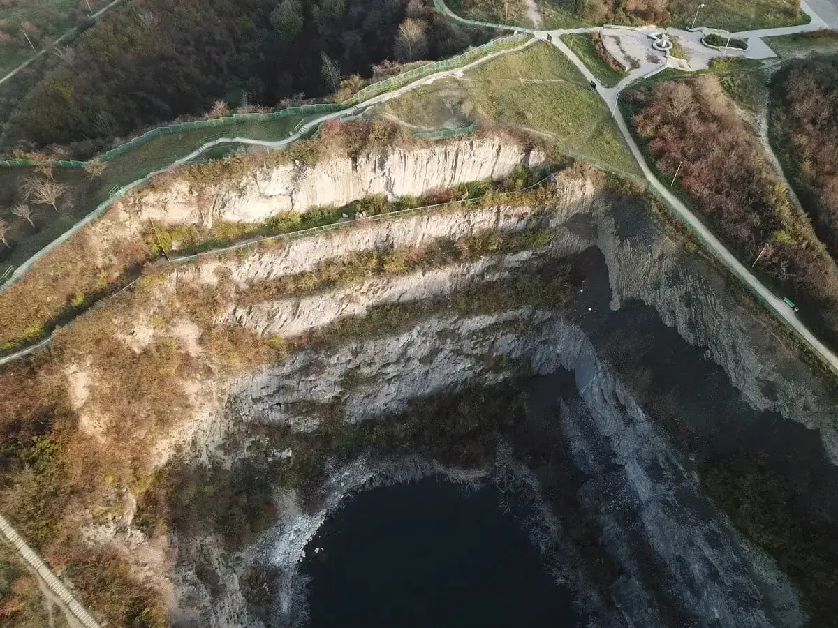 Widok z lotu ptaka na rezerwat Ślichowice z kamieniołomem i zbiornikiem wodnym. Ścieżki spacerowe biegną wzdłuż krawędzi.