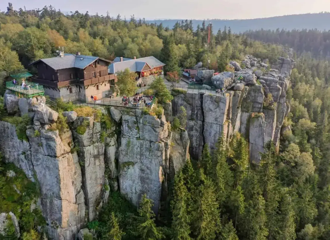 G&oacute;ry Stołowe atrakcje: schroniska i tarasy widokowe na skalnych urwiskach, otoczone lasem.