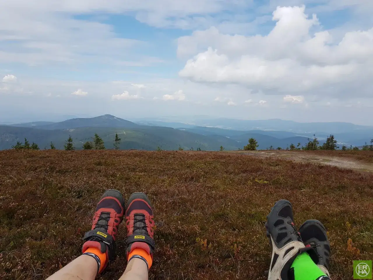 Widok z śnieżnik szczyt na rozległe pasma g&oacute;rskie. Dwie pary but&oacute;w trekkingowych odpoczywają na wrzosowisku.