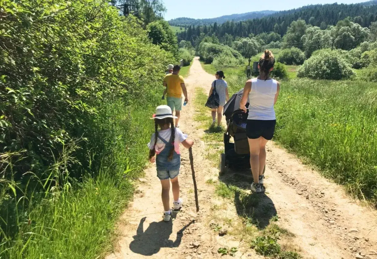 Rodzina spaceruje po malowniczej ścieżce, odkrywając szlaki turystyczne dla dzieci w okolicy Wisły.