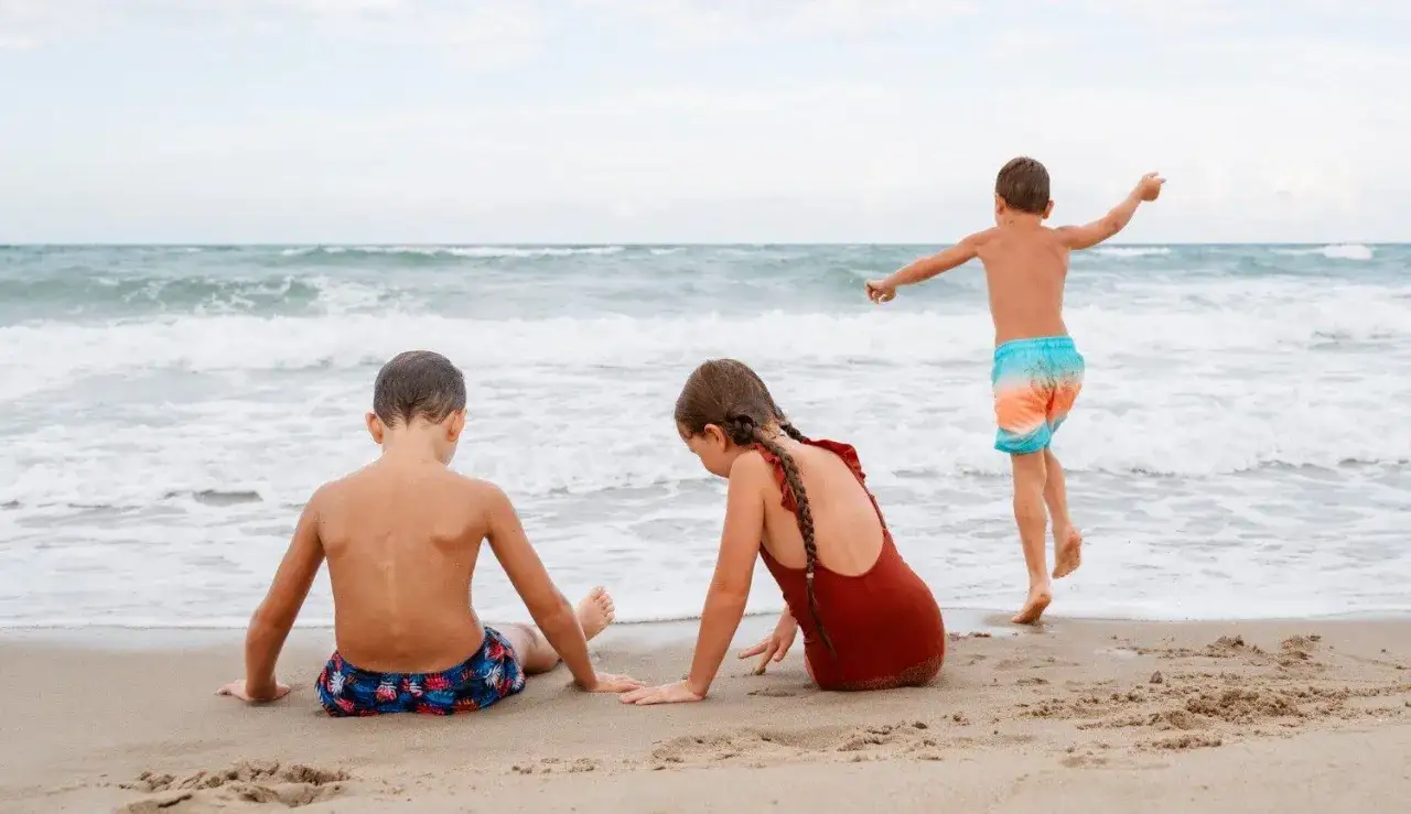 Dzieci bawią się na plaży w Jastarni. To świetne jastarnia atrakcje dla dzieci, gdzie można budować zamki z piasku i pluskać się w morzu.