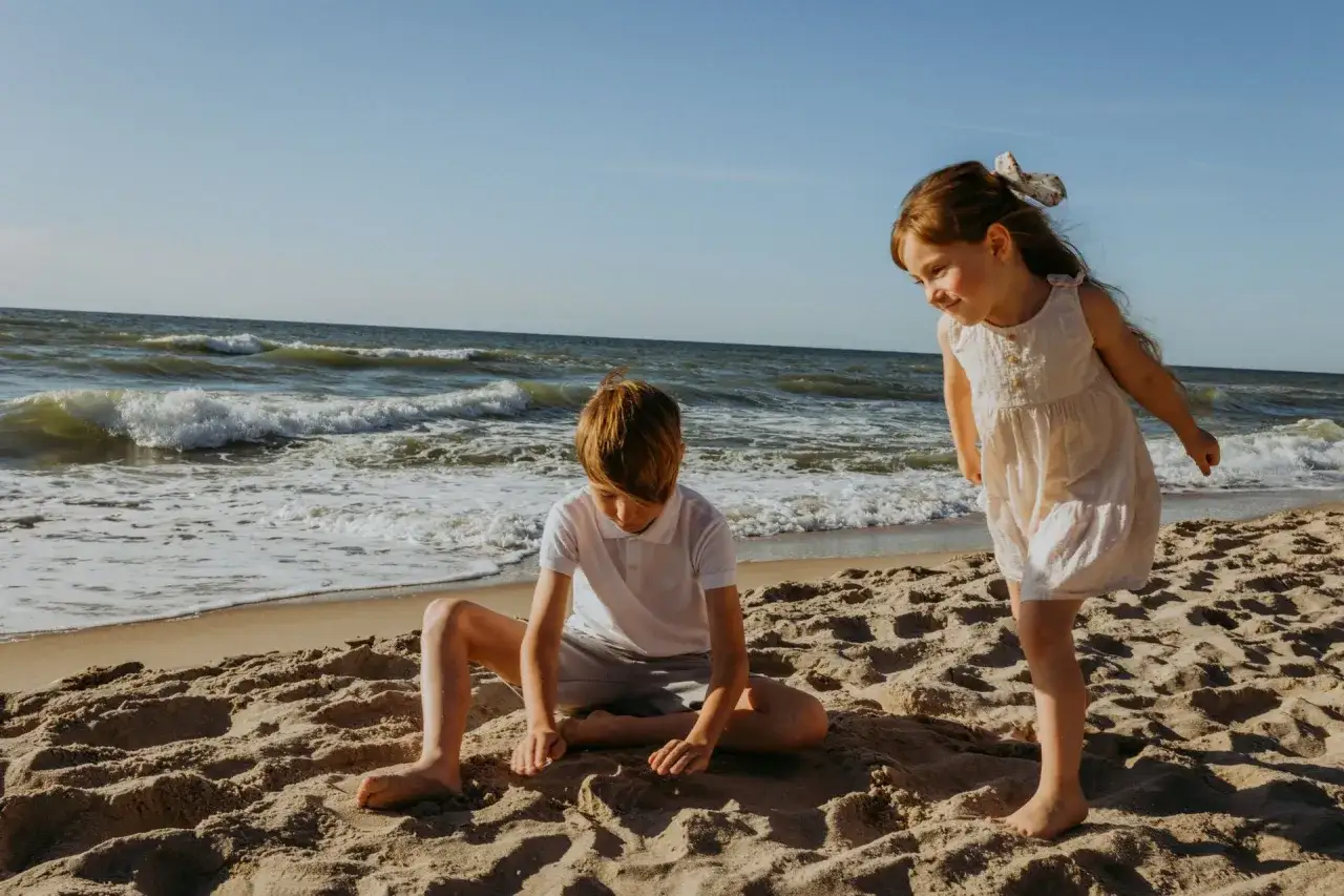Dzieci szukają bursztyn&oacute;w na plaży. To wspaniałe jantar atrakcje dla dzieci nad morzem.