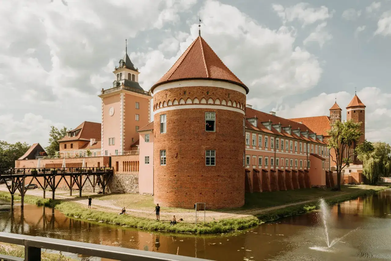 Zamek w Lidzbarku Warmińskim, jedna z głównych atrakcji regionu, otoczony fosą z fontanną.