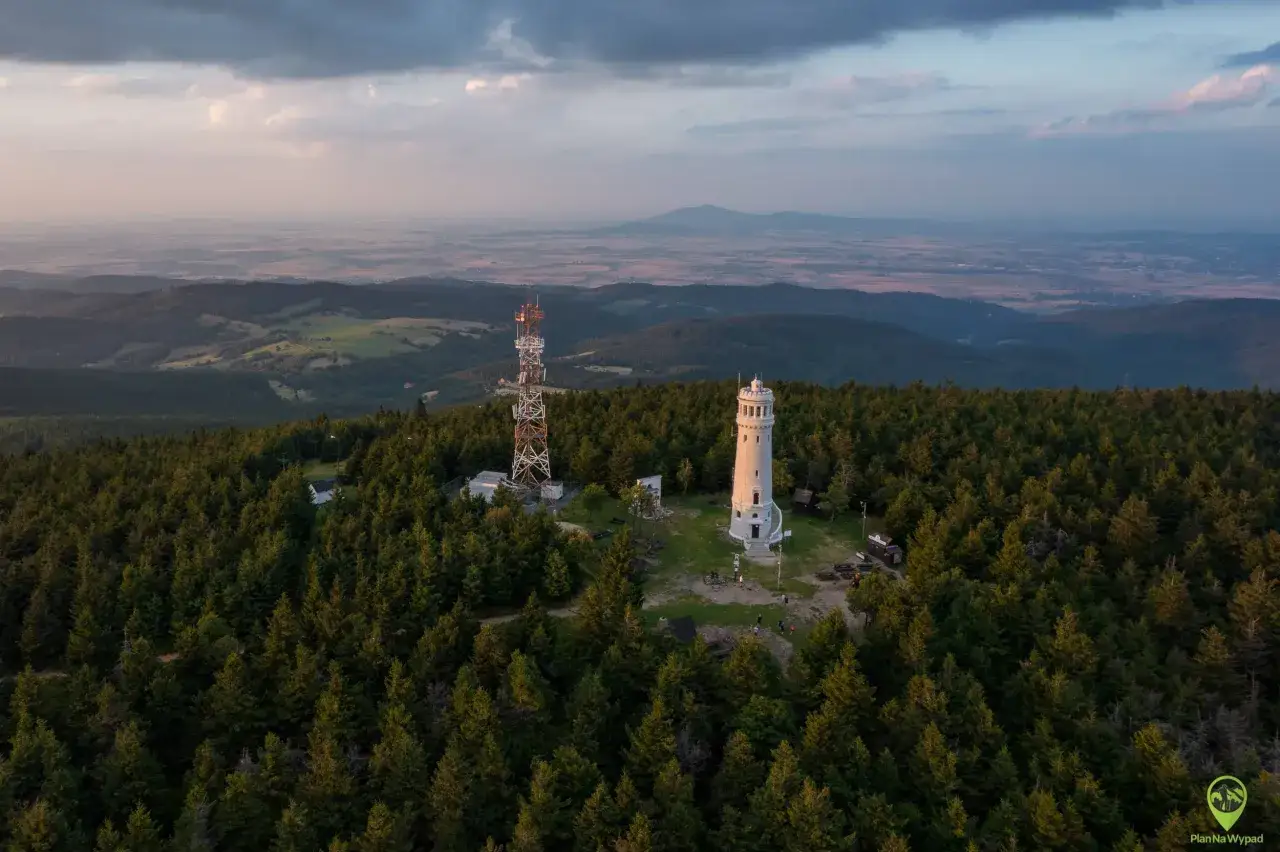 Wieża widokowa i maszt telekomunikacyjny na tle rozległej panoramy gór Sowich.